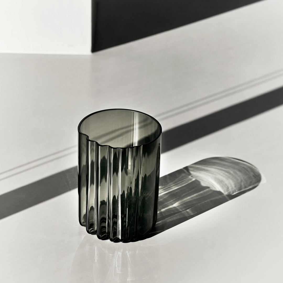 Pulse Vase — wide Smoke glass vase with ribbed side in sunlight on a pale surface, lifestyle view