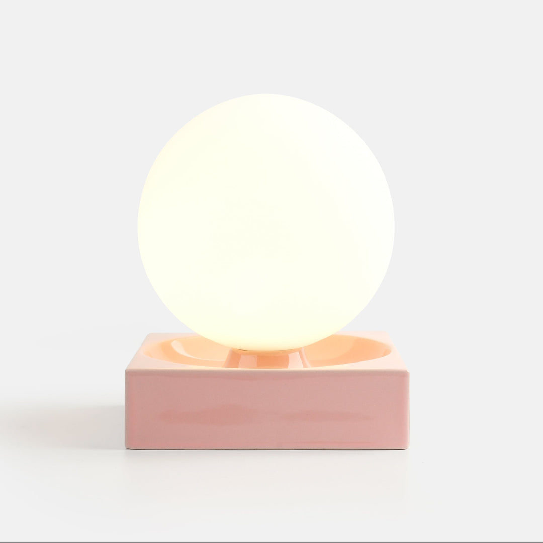 Glowing ceramic sphere lamp on blush pink base, modern designer home decor