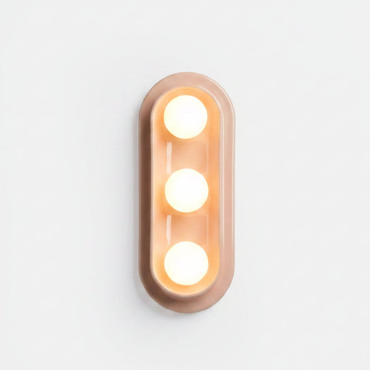 Modern oval wall sconce with three warm globe lights, matte blush finish, minimalist design