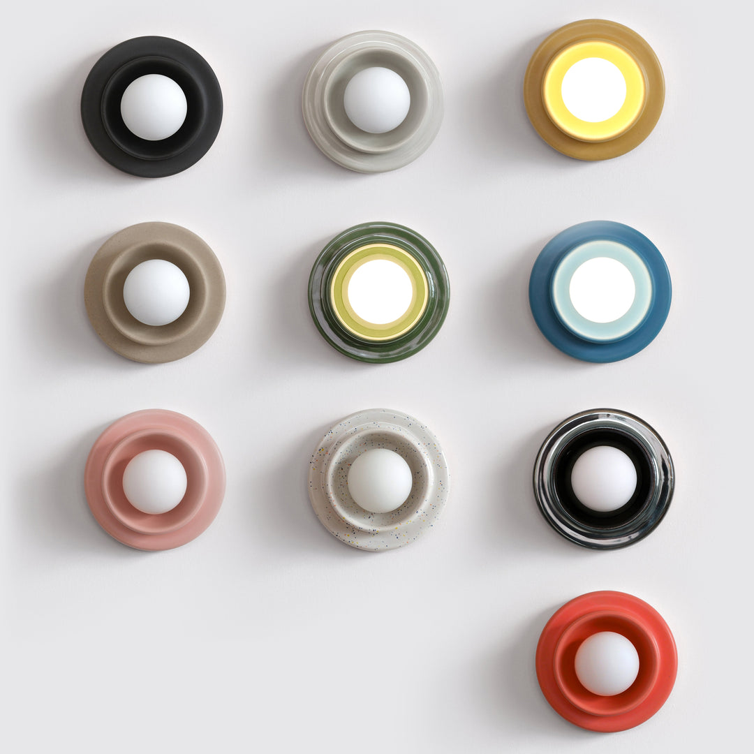 Ceramic wall sconces in assorted colors and finishes, modern sculptural design, arranged grid-style.