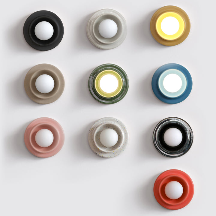 Ceramic wall sconces in assorted colors and finishes, modern sculptural design, arranged grid-style.