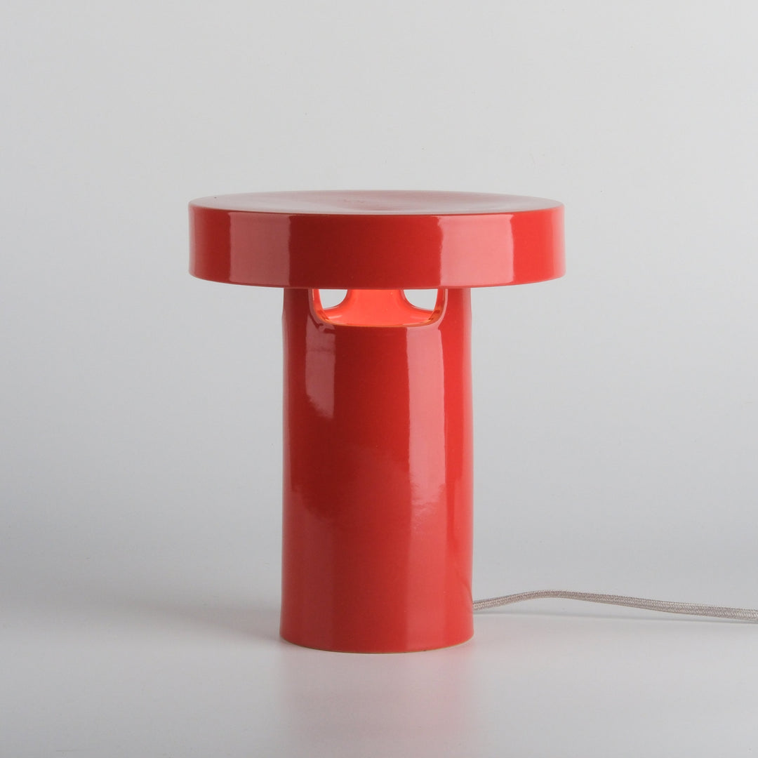 Glossy red ceramic table lamp with minimalist design and soft glow