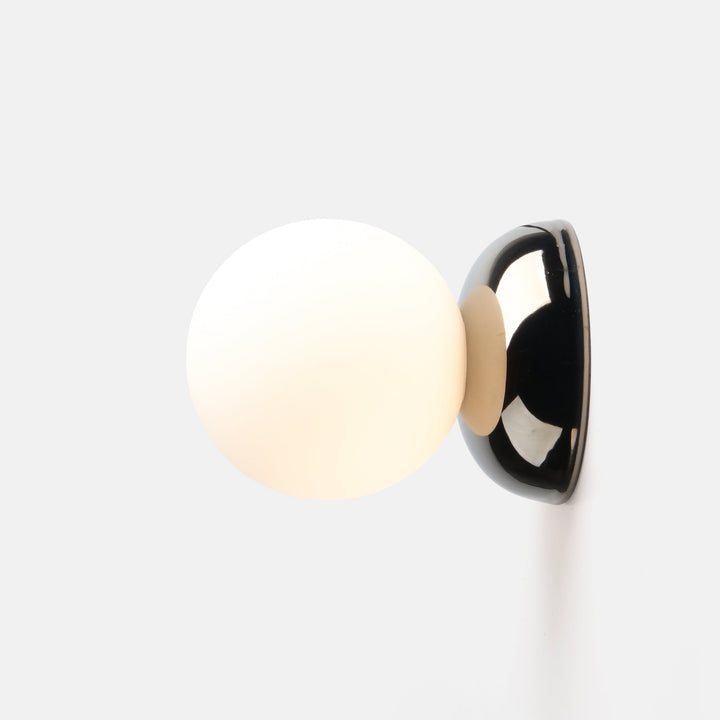 Sleek wall sconce with frosted glass globe and polished chrome base, modern minimalist design