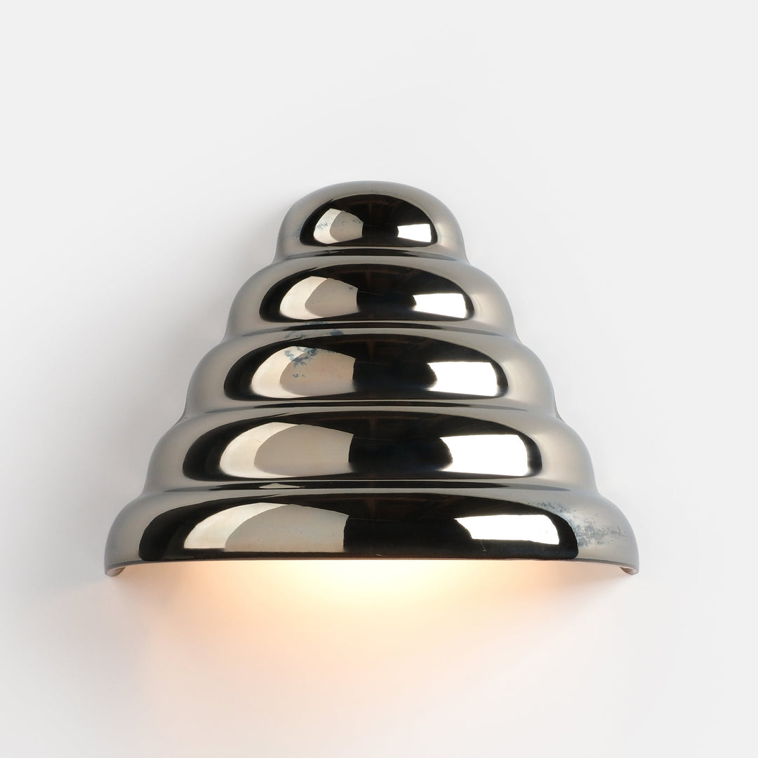 Sleek chrome wall sconce with tiered design, emitting warm ambient glow