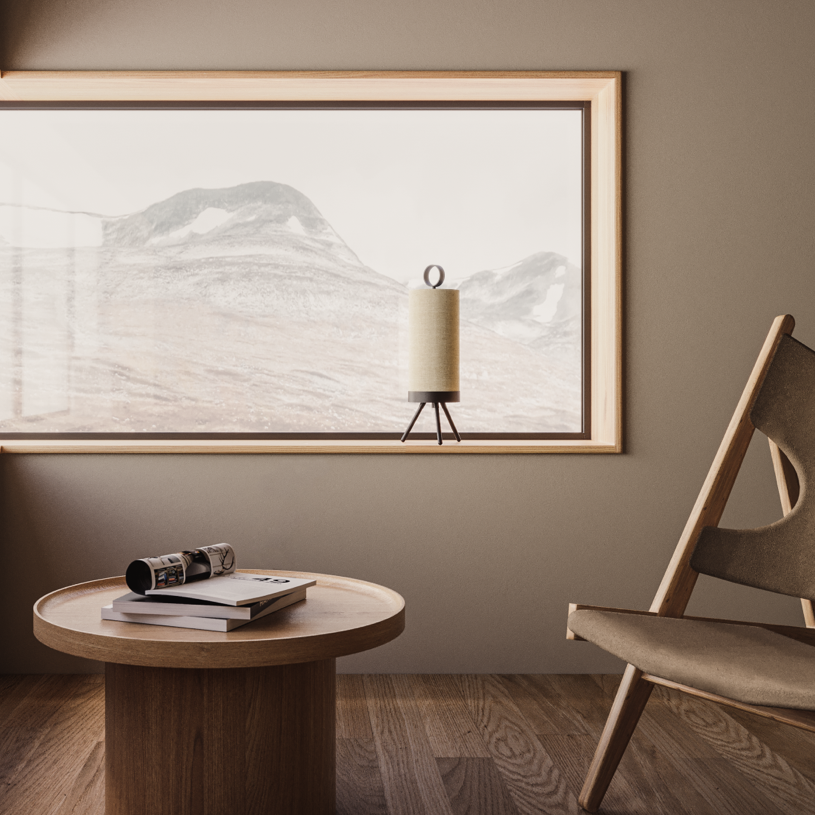 Linen cylinder lamp on a window ledge above a round wood side table and leather sling chair