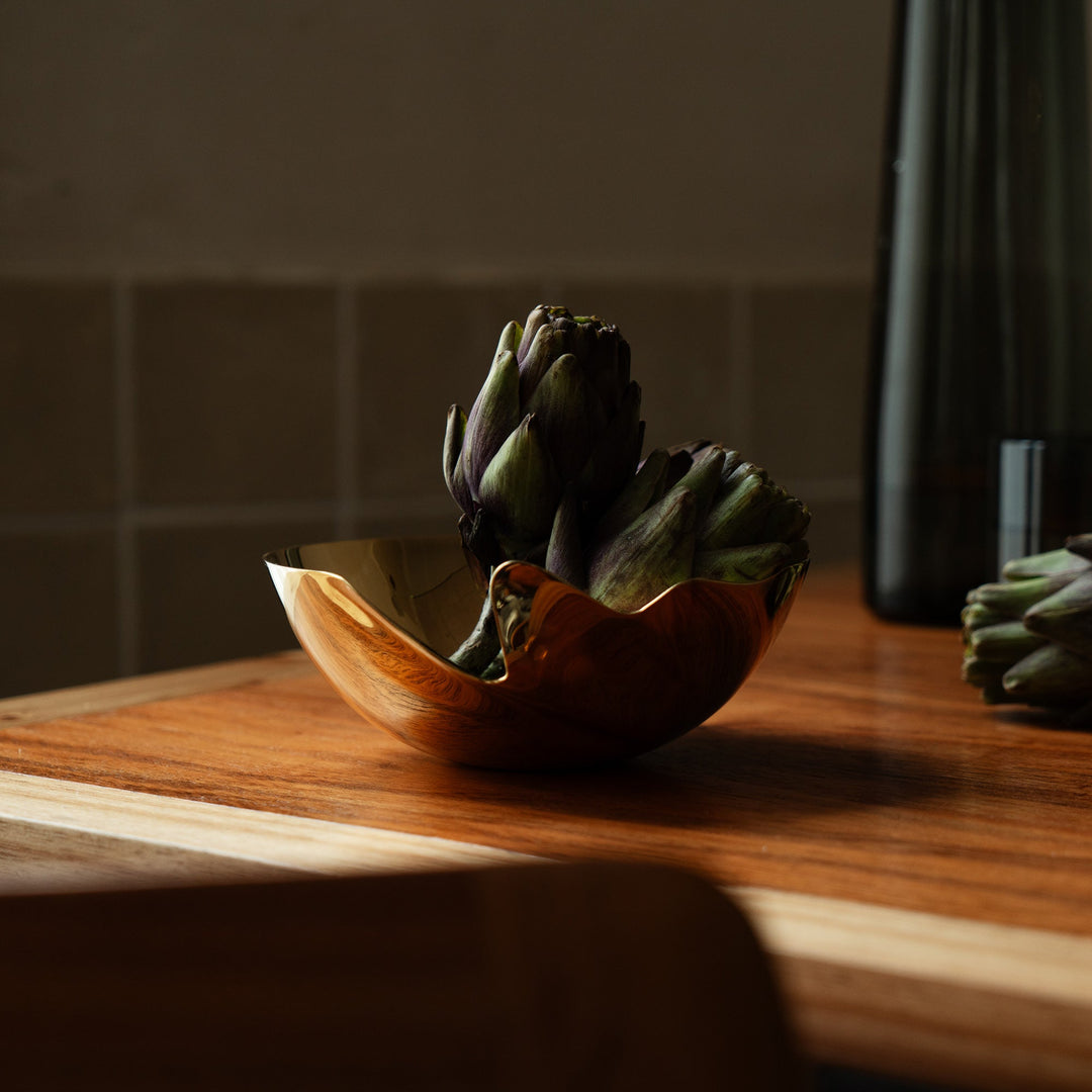 Serenity Bowl — gold bowl holding artichokes on a wooden counter in soft daylight