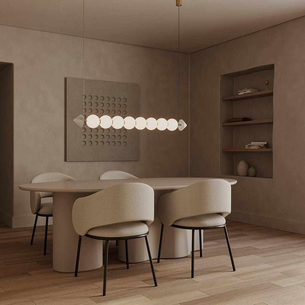 Soko Pendant Lamp lit above an oval dining table with upholstered chairs and wall shelving