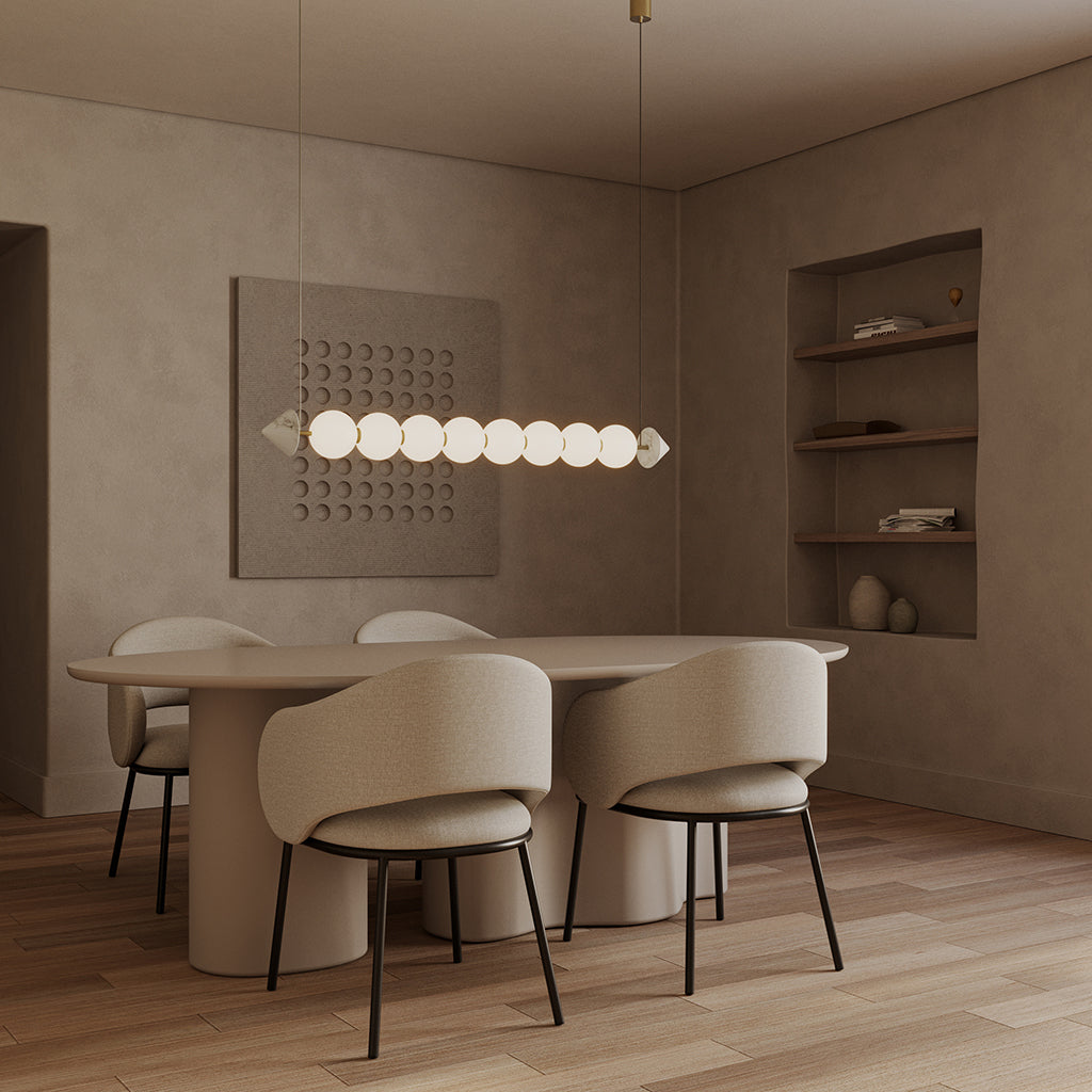 Soko Pendant Lamp lit above an oval dining table with upholstered chairs and wall shelving
