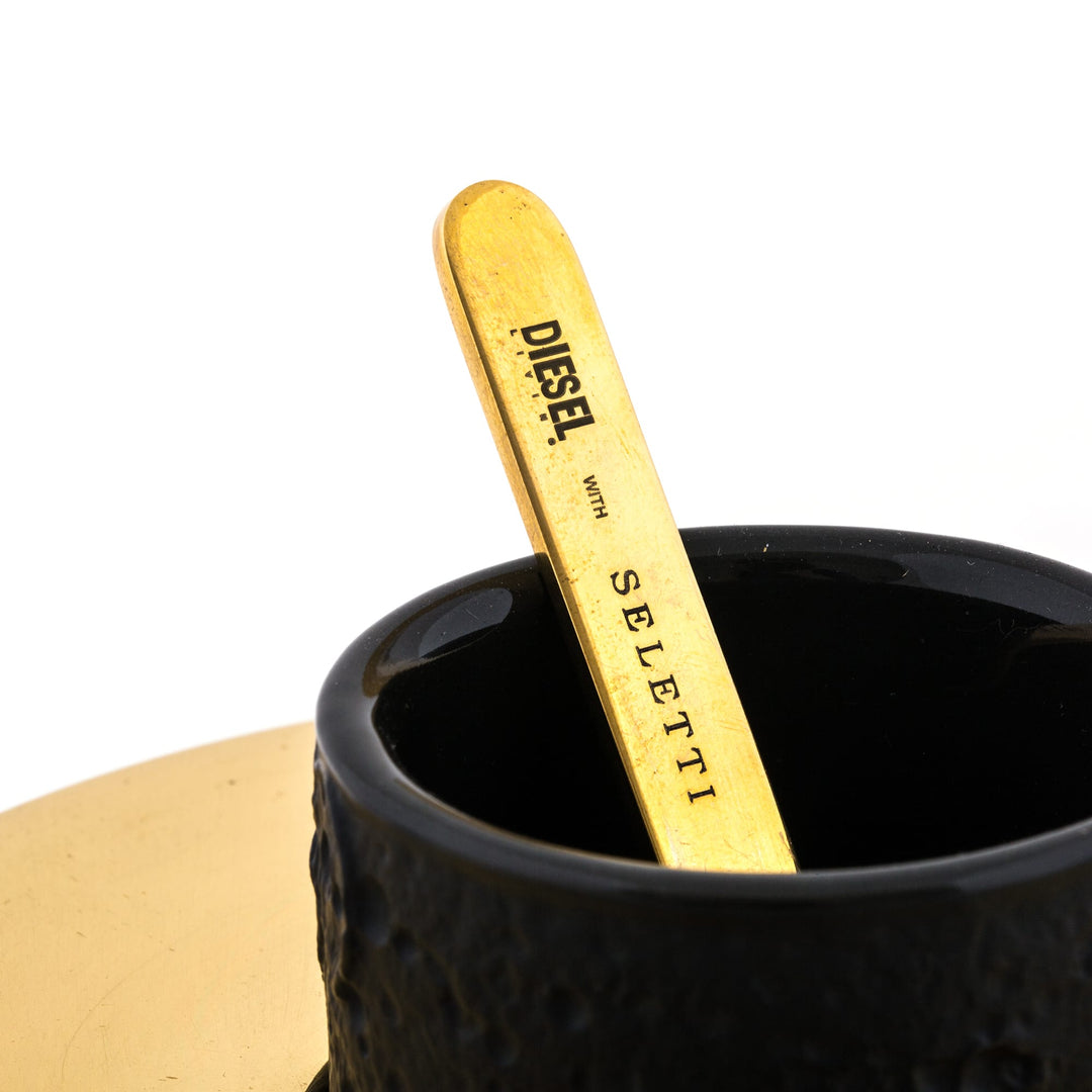 Seletti Cosmic Diner Lunar Coffee Set, close-up of the brass stirrer stamped Diesel Seletti in the black cup
