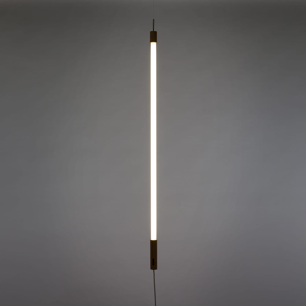 Seletti Linea LED White, white tube glowing upright against a gray wall
