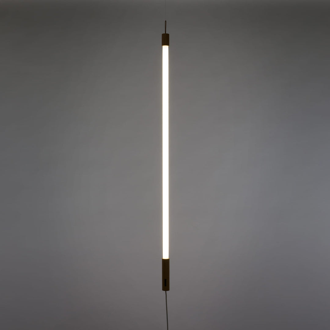 Seletti Linea LED White, white tube glowing upright against a gray wall