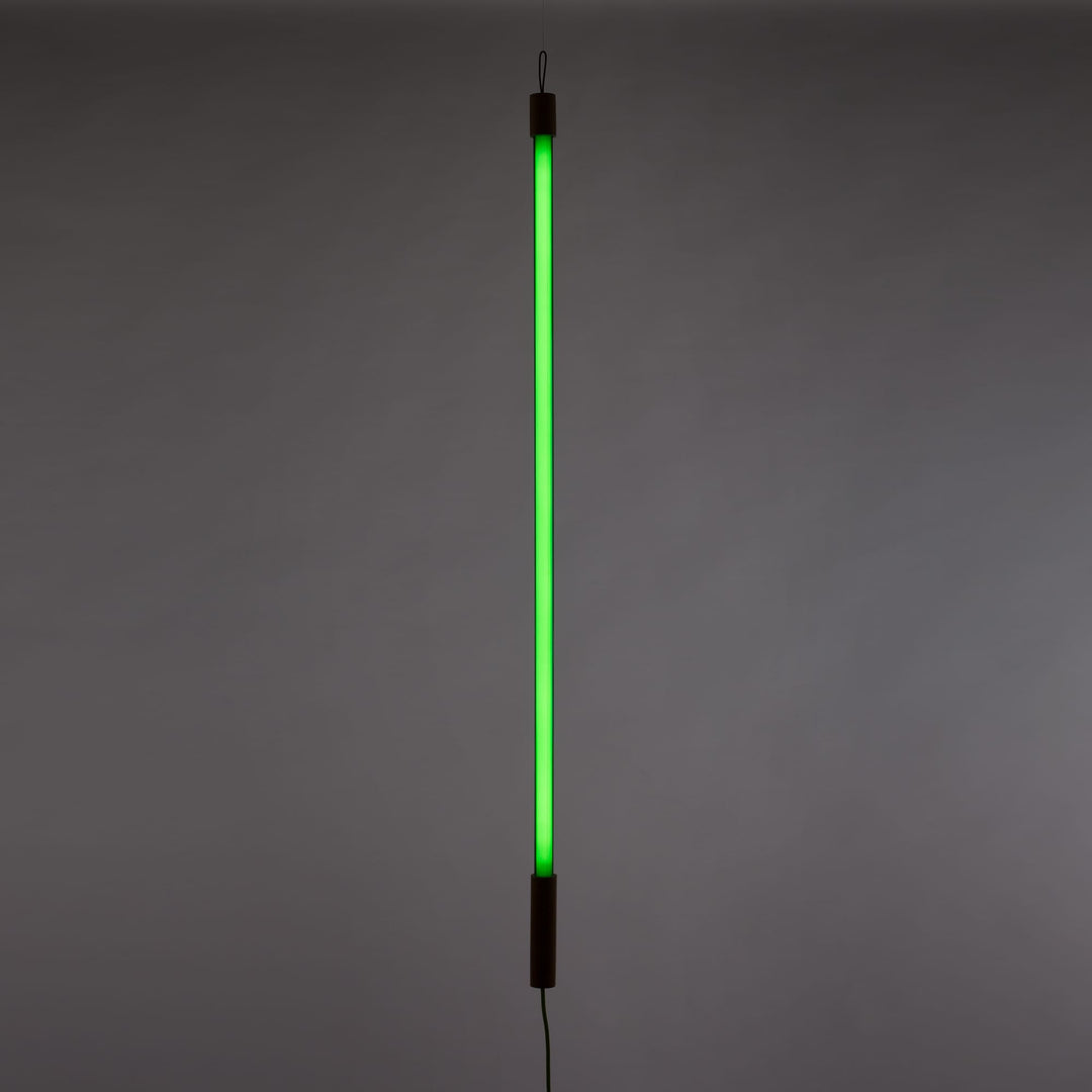 Seletti Linea LED Green, green tube glowing upright against a dark gray wall
