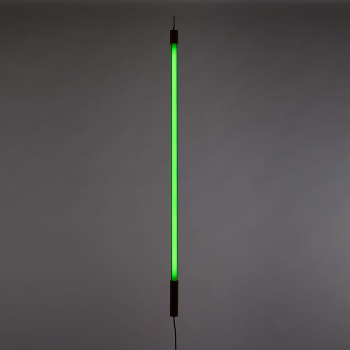 Seletti Linea LED Green, green tube glowing upright against a dark gray wall