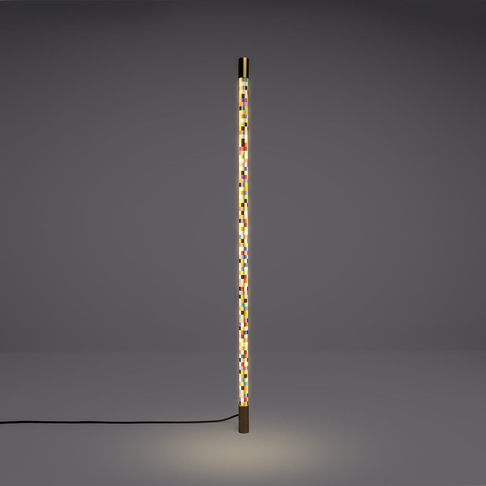 Seletti Linea Pixled, pixel tube lit upright against a gray wall, glow pooling on the floor