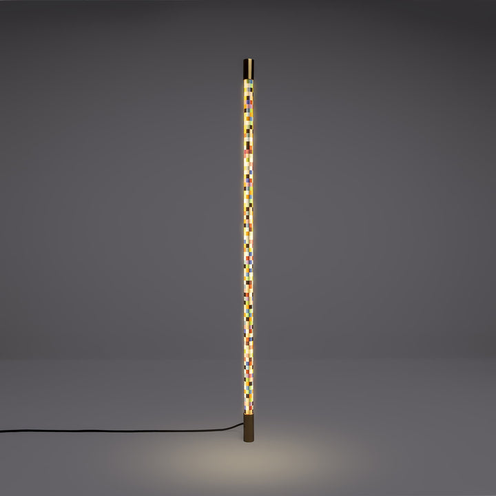 Seletti Linea Pixled, pixel tube lit upright against a gray wall, glow pooling on the floor