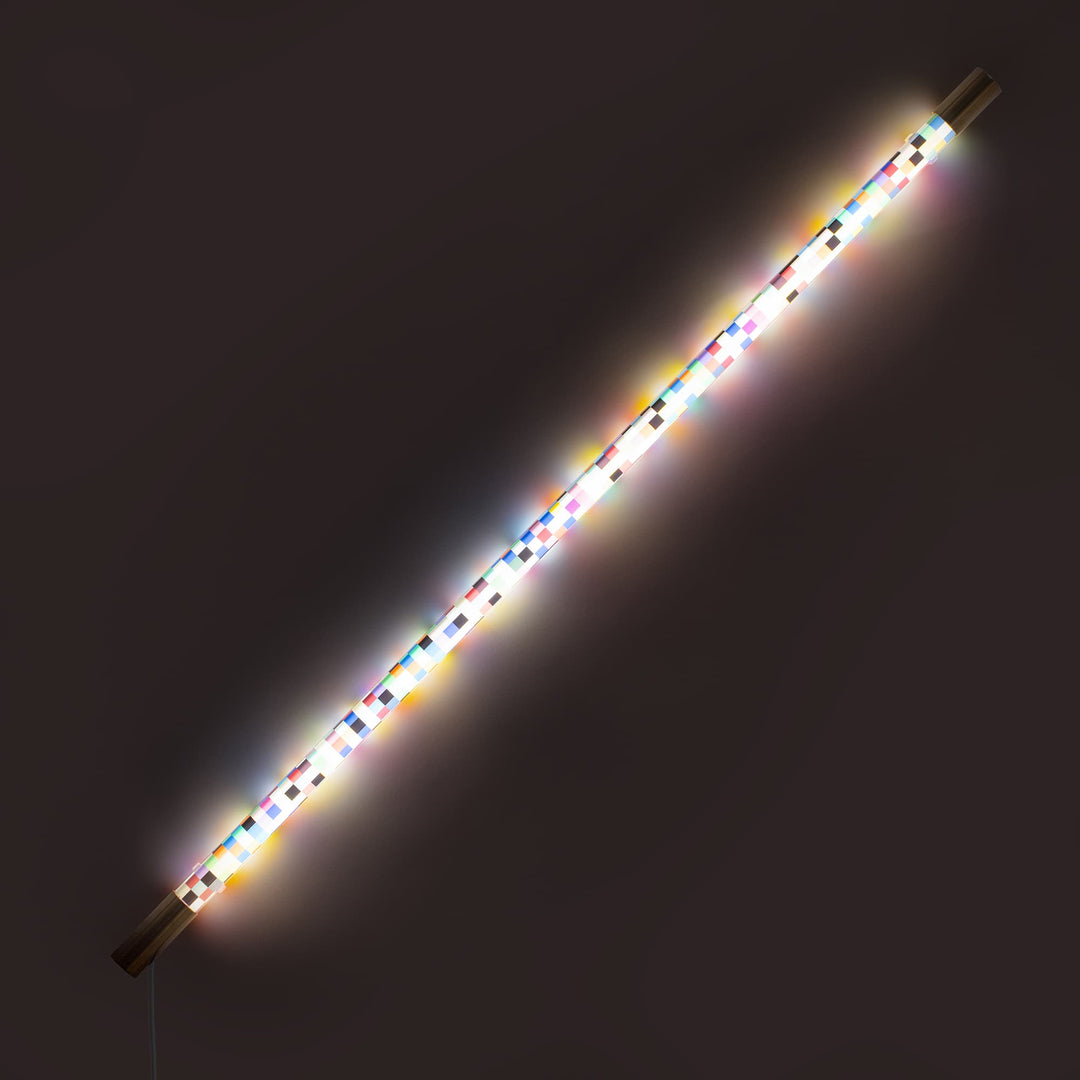 Seletti Linea Pixled, pixel tube glowing white and rainbow on the diagonal against a dark wall