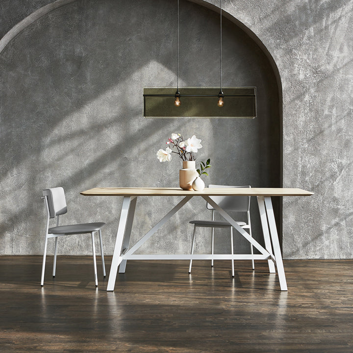 Modern oak dining table with white metal trestle legs, styled with minimalist chairs and floral centerpiece