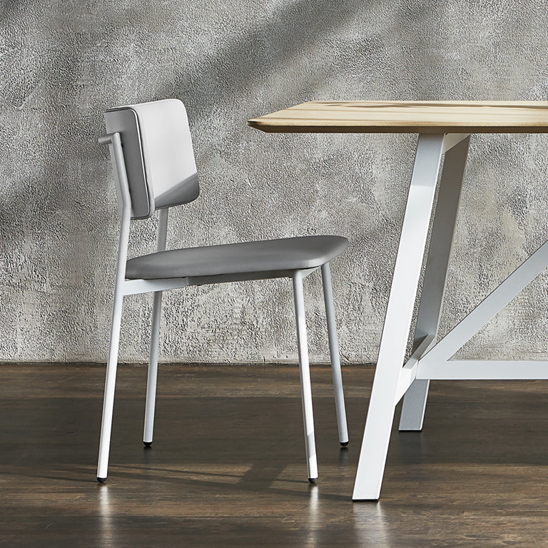Modern gray upholstered chair with white metal legs beside minimalist wooden table