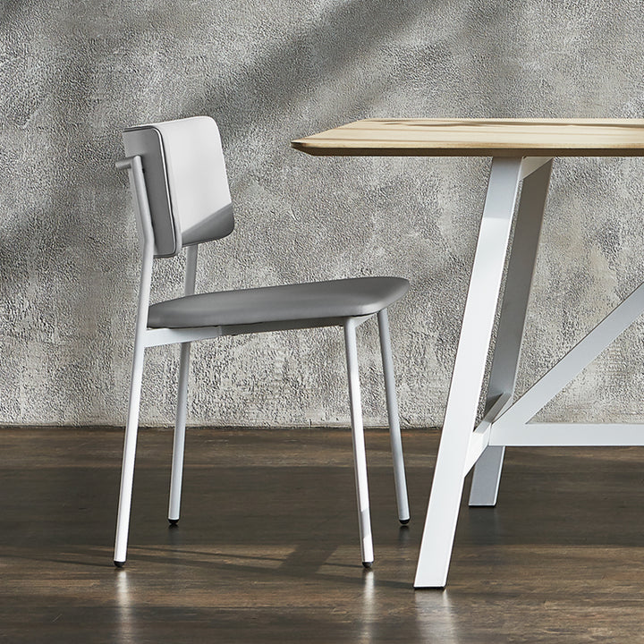 Modern gray upholstered chair with white metal legs beside minimalist wooden table