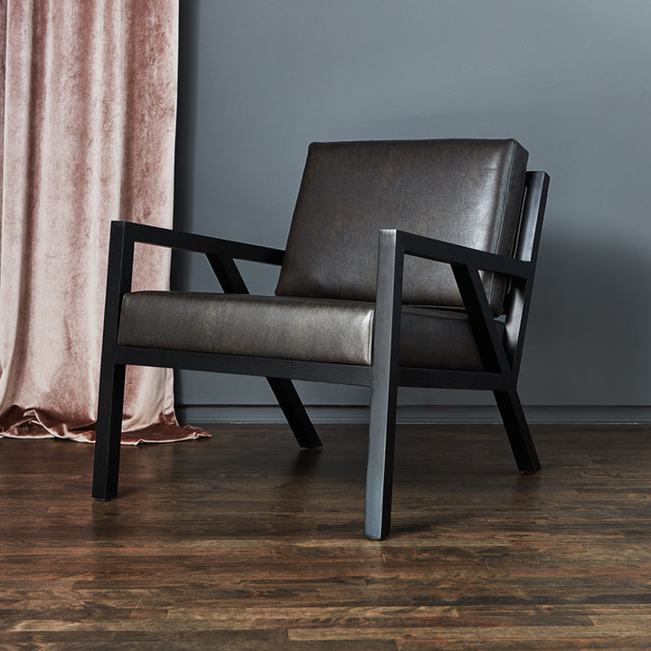 Dark leather armchair with sleek black frame, styled beside blush velvet curtain