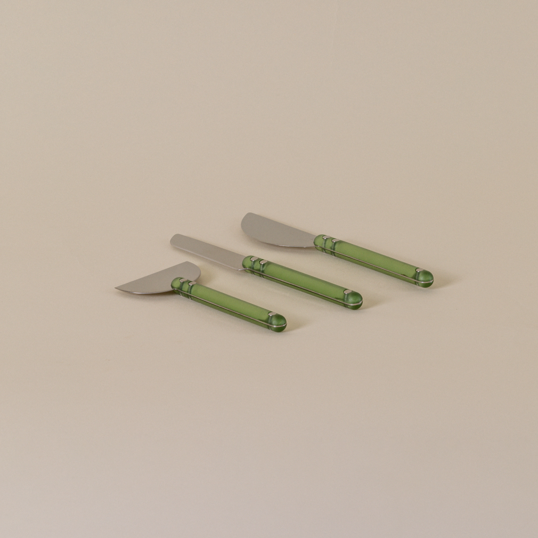 Four green knives with decorative handles on a beige background