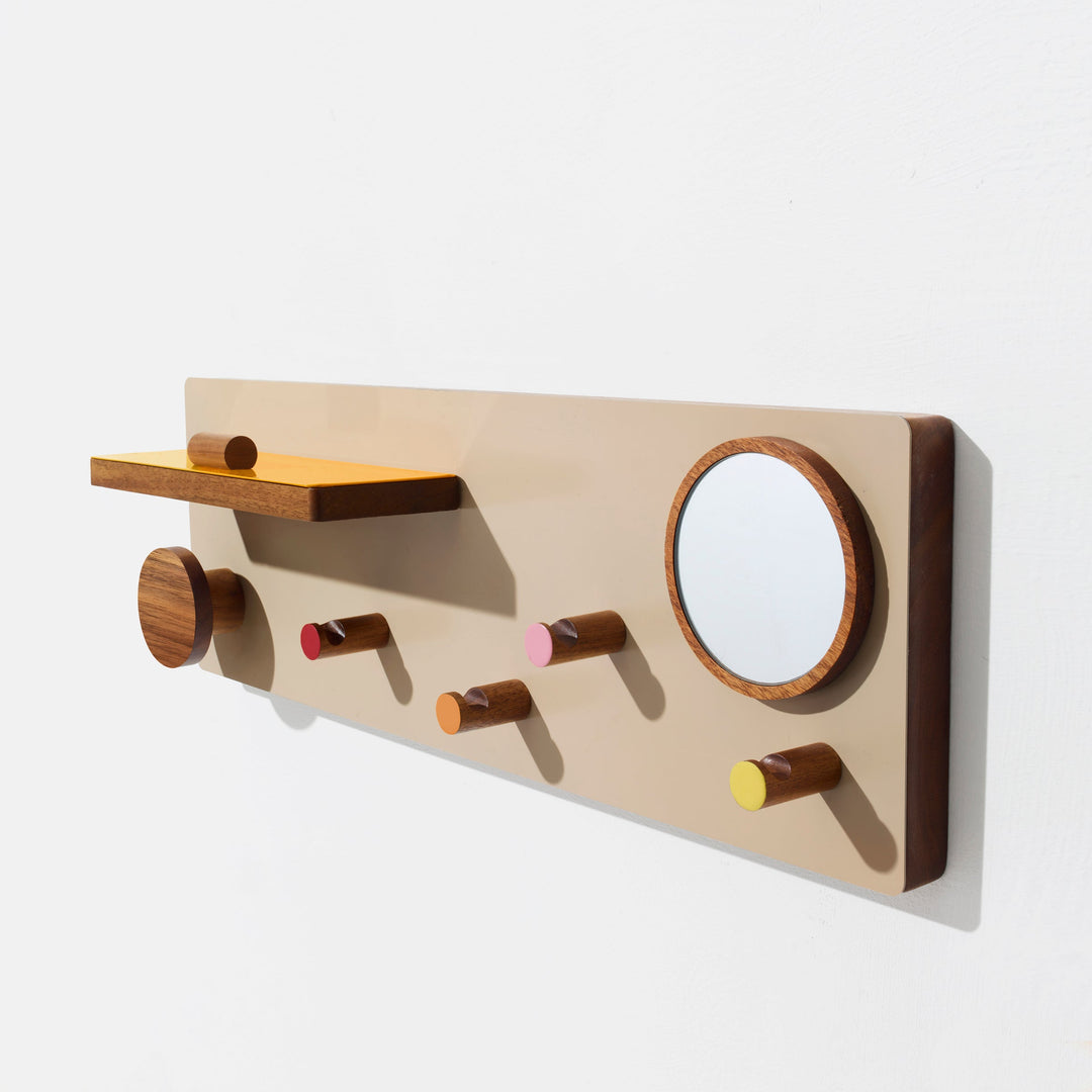 Modern walnut wall organizer with colored pegs, round mirror, and floating shelf.