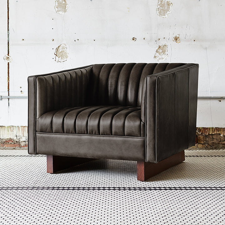 Dark leather armchair with ribbed detailing and wooden legs