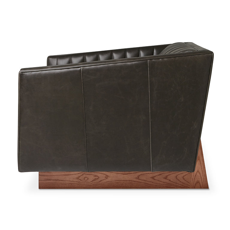 Dark leather sofa with tufted backrest and walnut wood base, designer home furnishing