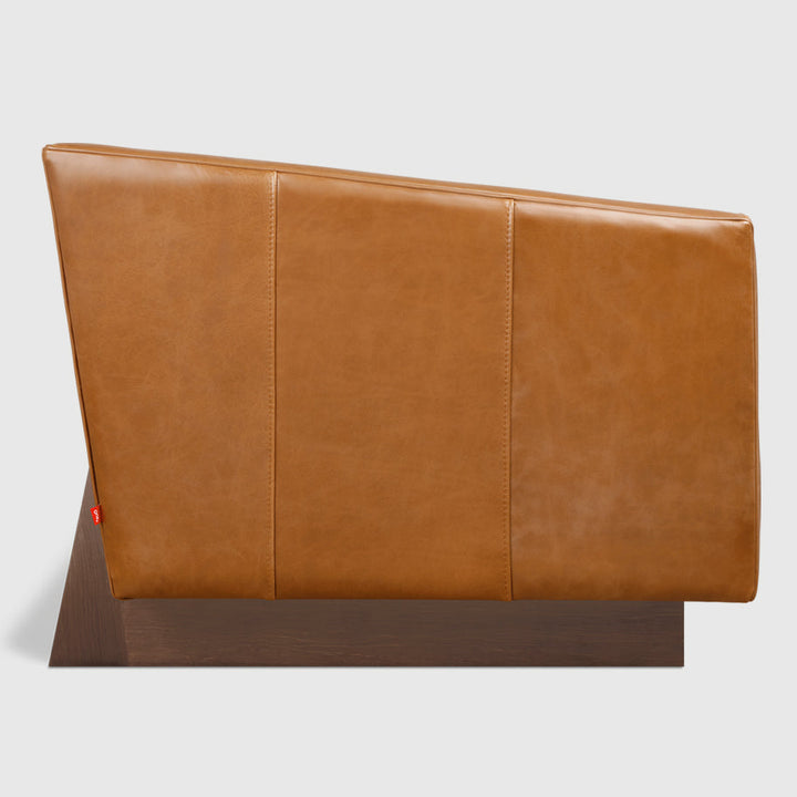 Caramel leather headboard with tailored stitching, mounted on a walnut base