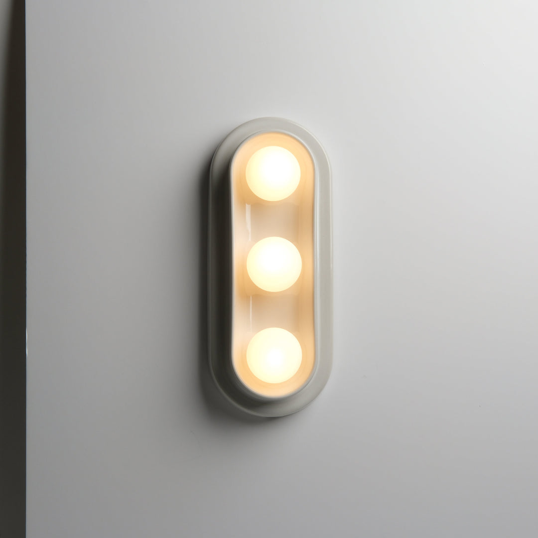 Modern oval wall sconce with three warm bulbs, sleek matte finish
