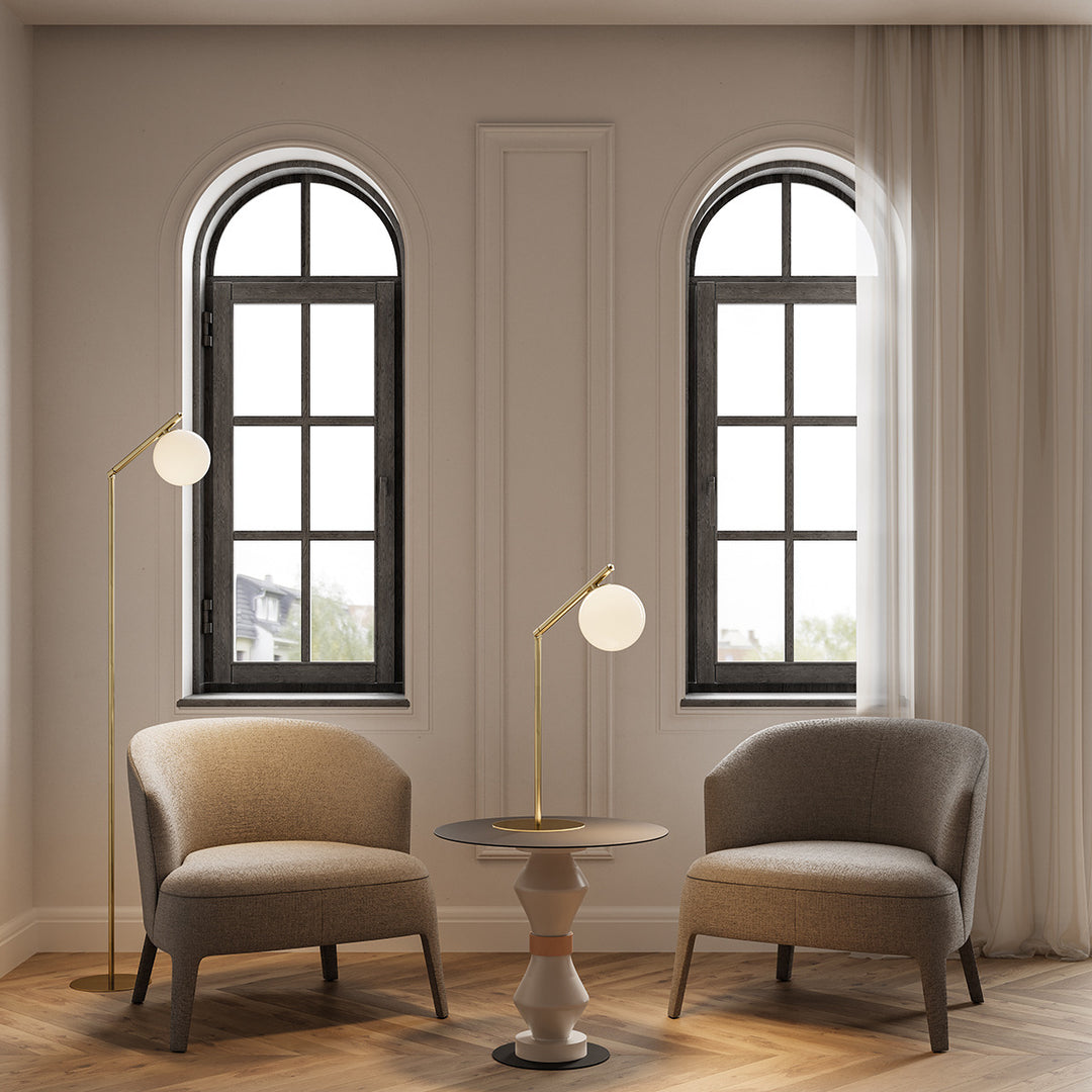 Brass Endo Floor Lamp beside a beige armchair in a room with arched windows, with a matching table lamp