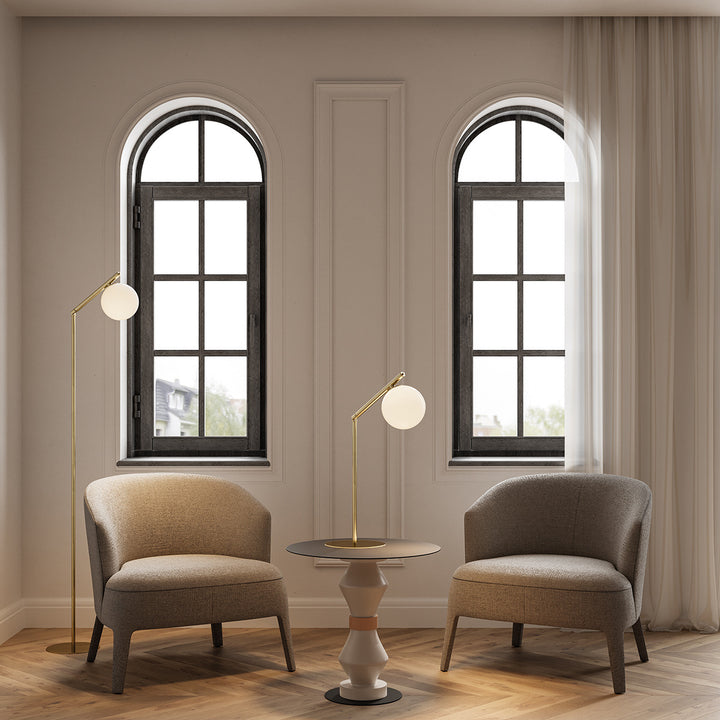 Brass Endo Floor Lamp beside a beige armchair in a room with arched windows, with a matching table lamp