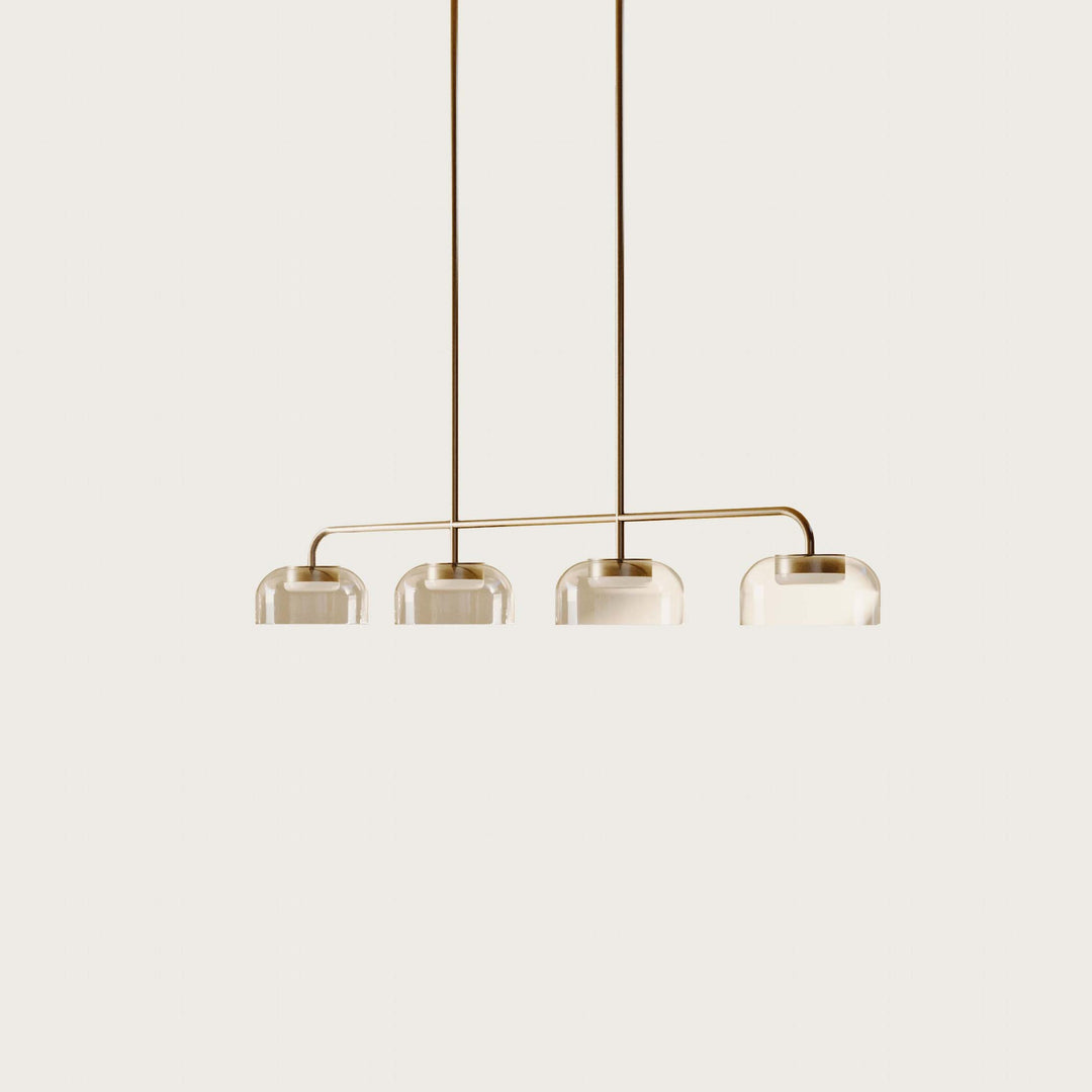 Ipon Linear Pendant in aged gold with four clear glass domes on two rods, lit, on a pale backdrop