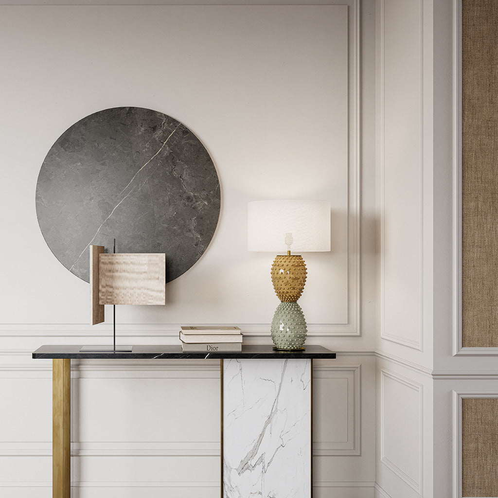 Cactus Table Lamp with studded amber and sage glass base on a black marble console before a round stone wall disc