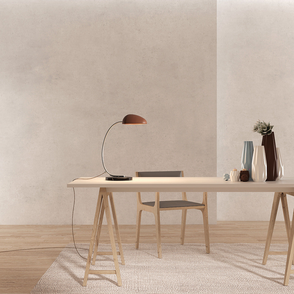 Kezo Table Lamp with a rust dome shade on a trestle desk beside ceramic vases and a wooden chair