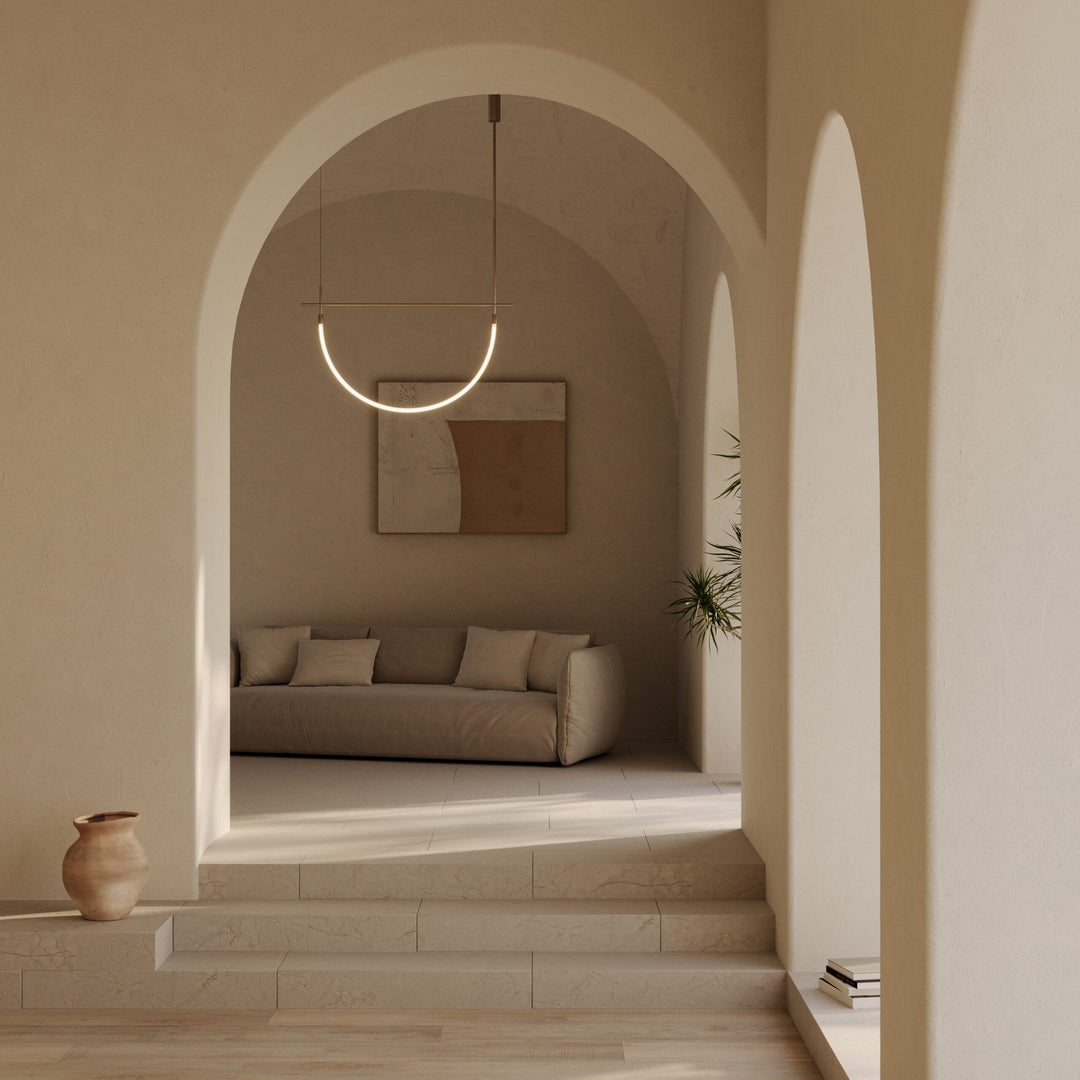 Cram Pendant lit, glowing arc tube hanging in a stone archway above a linen sofa and wall art