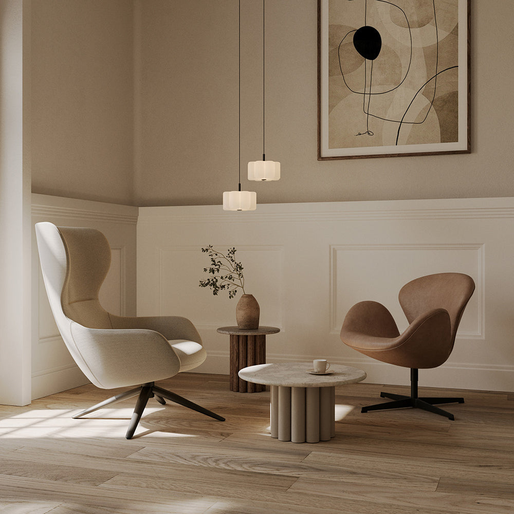 Two Flow Pendants at staggered heights above a travertine coffee table between lounge chairs in a panelled room
