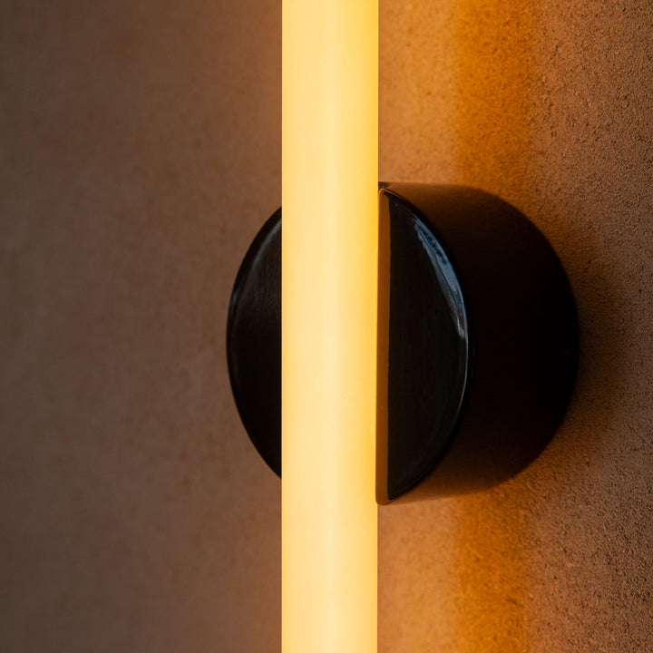 Sleek black ceramic wall sconce with warm vertical glow