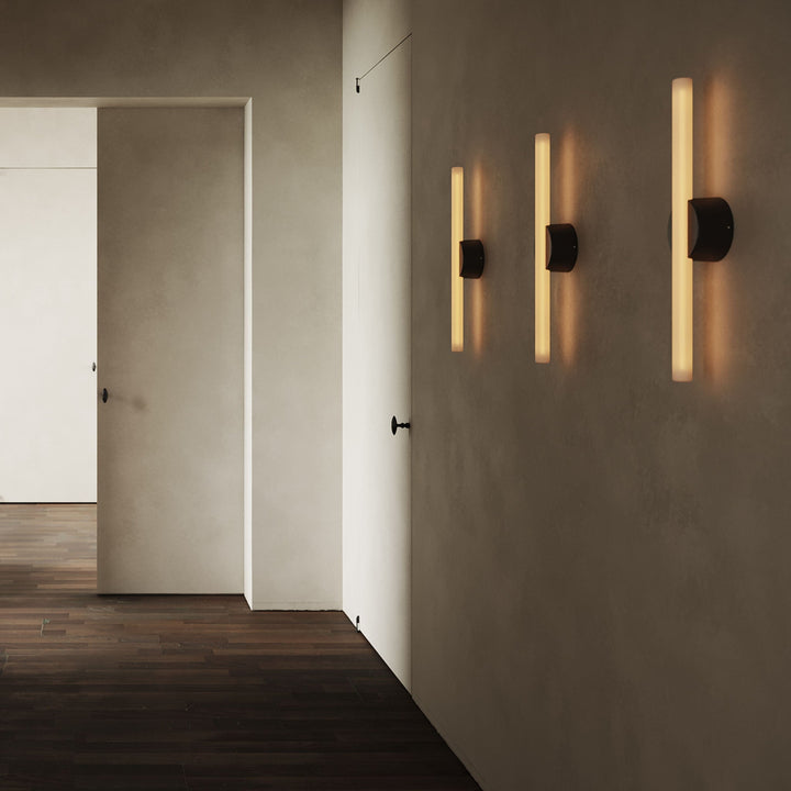 Modern wall sconce with matte black finish and warm LED glow, minimalist hallway lighting design