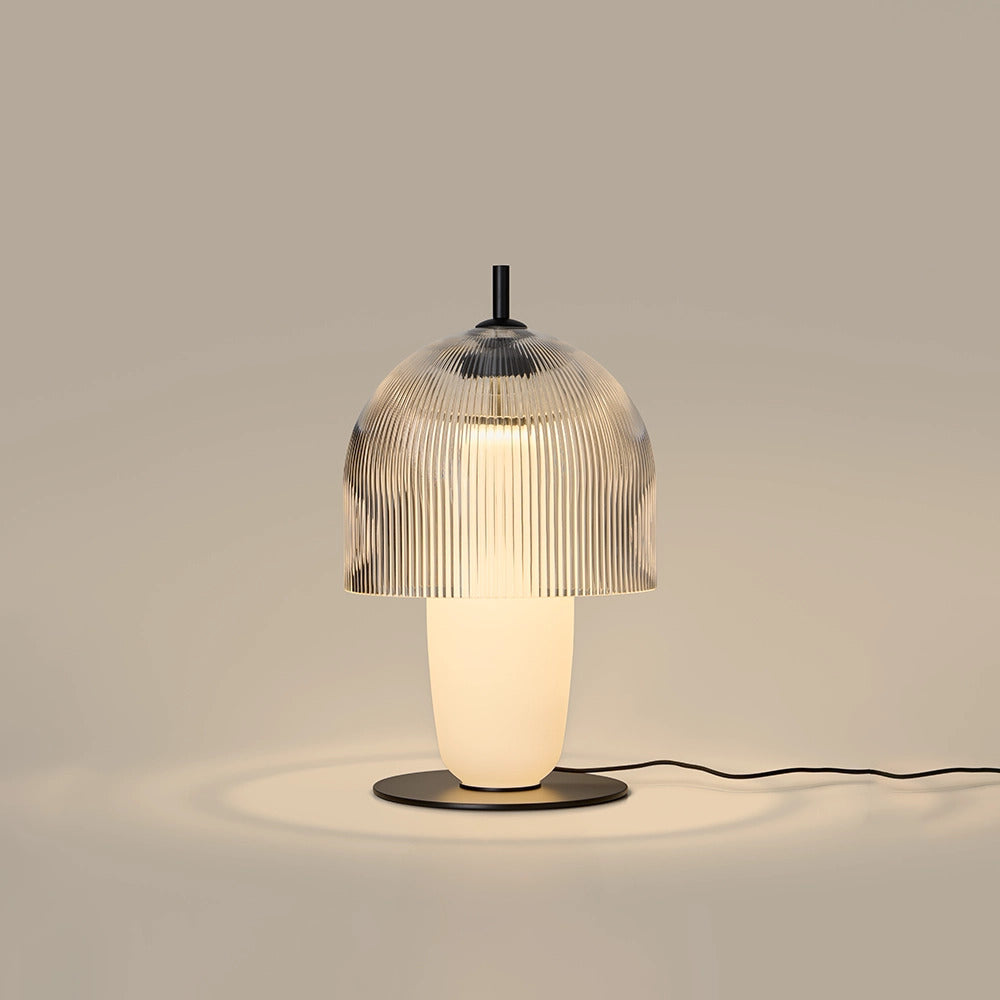 Holm Table Lamp lit, warm light glowing through the ribbed glass dome and opal body