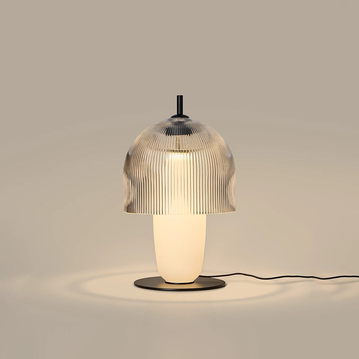 Holm Table Lamp lit, warm light glowing through the ribbed glass dome and opal body