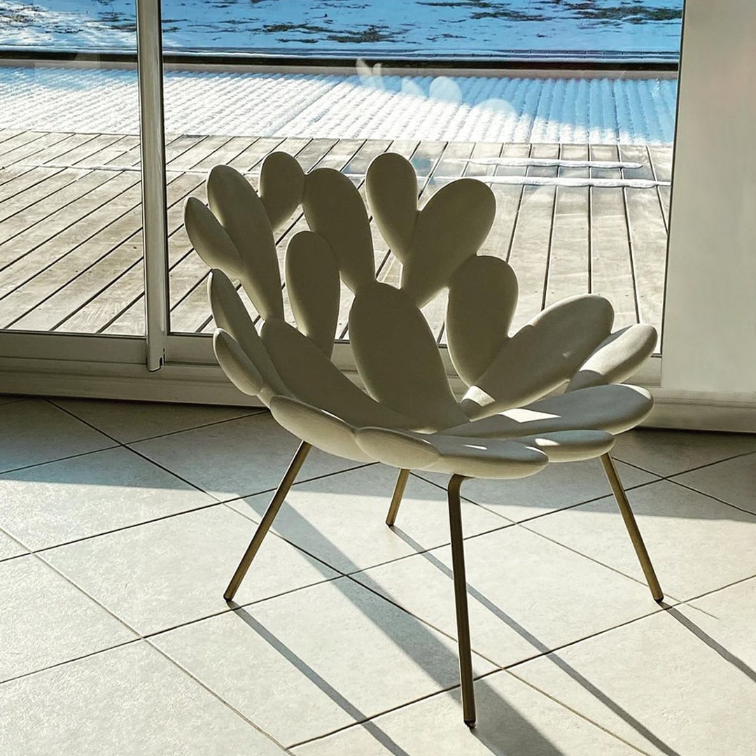 Filicudi armchair by Marcantonio, sculptural polyethylene seat on slim brass legs, poolside setting.