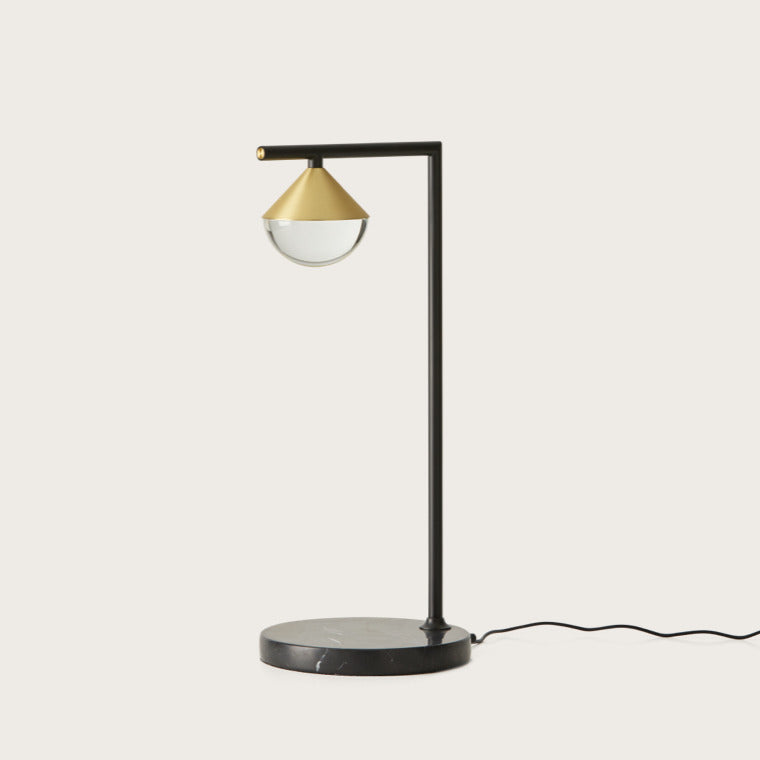 Nino Table Lamp, black L-shaped arm with brass cone and clear glass dome on a black marble base, by Aromas del Campo