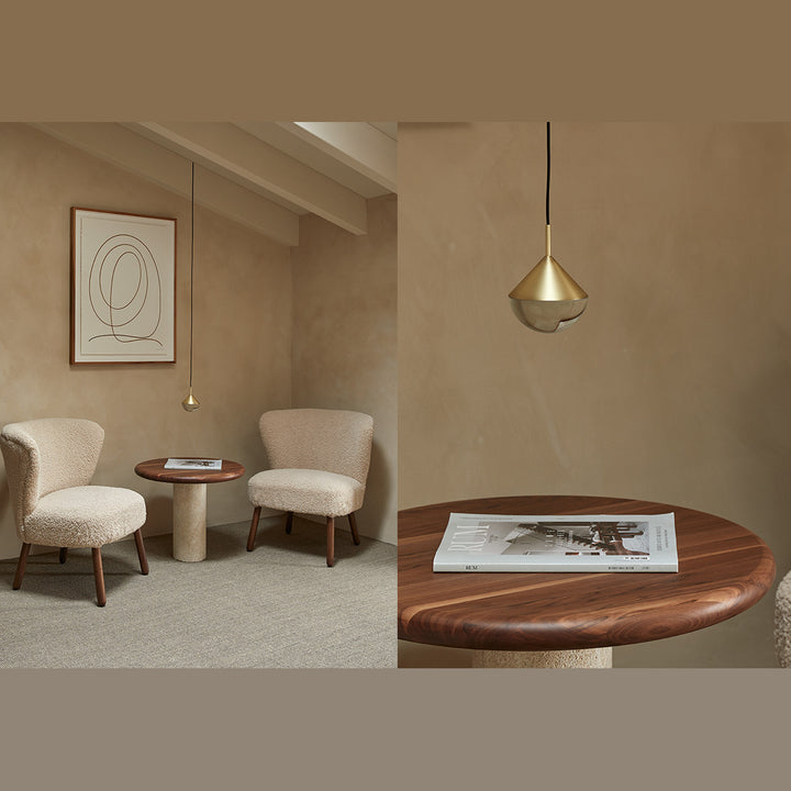 Brass Nino Pendant Lamp hanging over a round walnut side table between two boucle armchairs