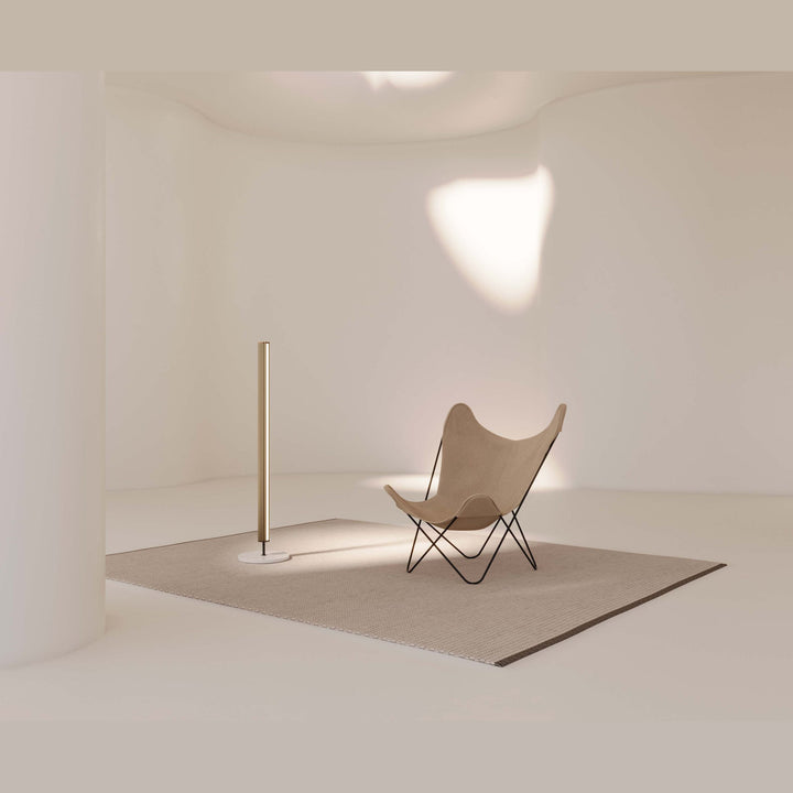 Niro Floor Lamp in a curved minimal room beside a butterfly chair on a large rug
