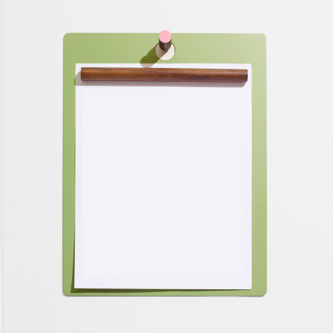 Sleek green clipboard with wooden clip and pink accent, minimalist home office decor