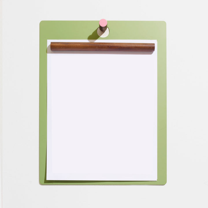 Sleek green clipboard with wooden clip and pink accent, minimalist home office decor