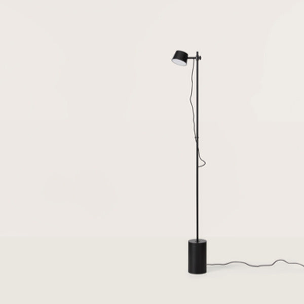 Black floor lamp with adjustable drum head on a slim pole and round weighted base, full view
