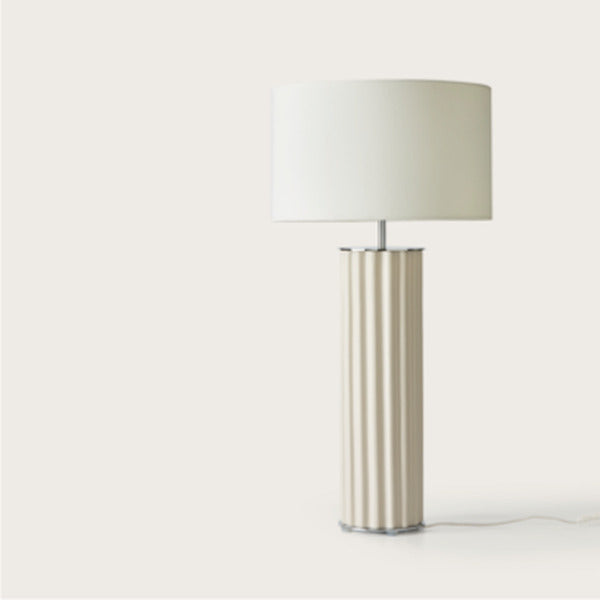 Cream fluted ceramic table lamp with white drum shade, front view on a light background