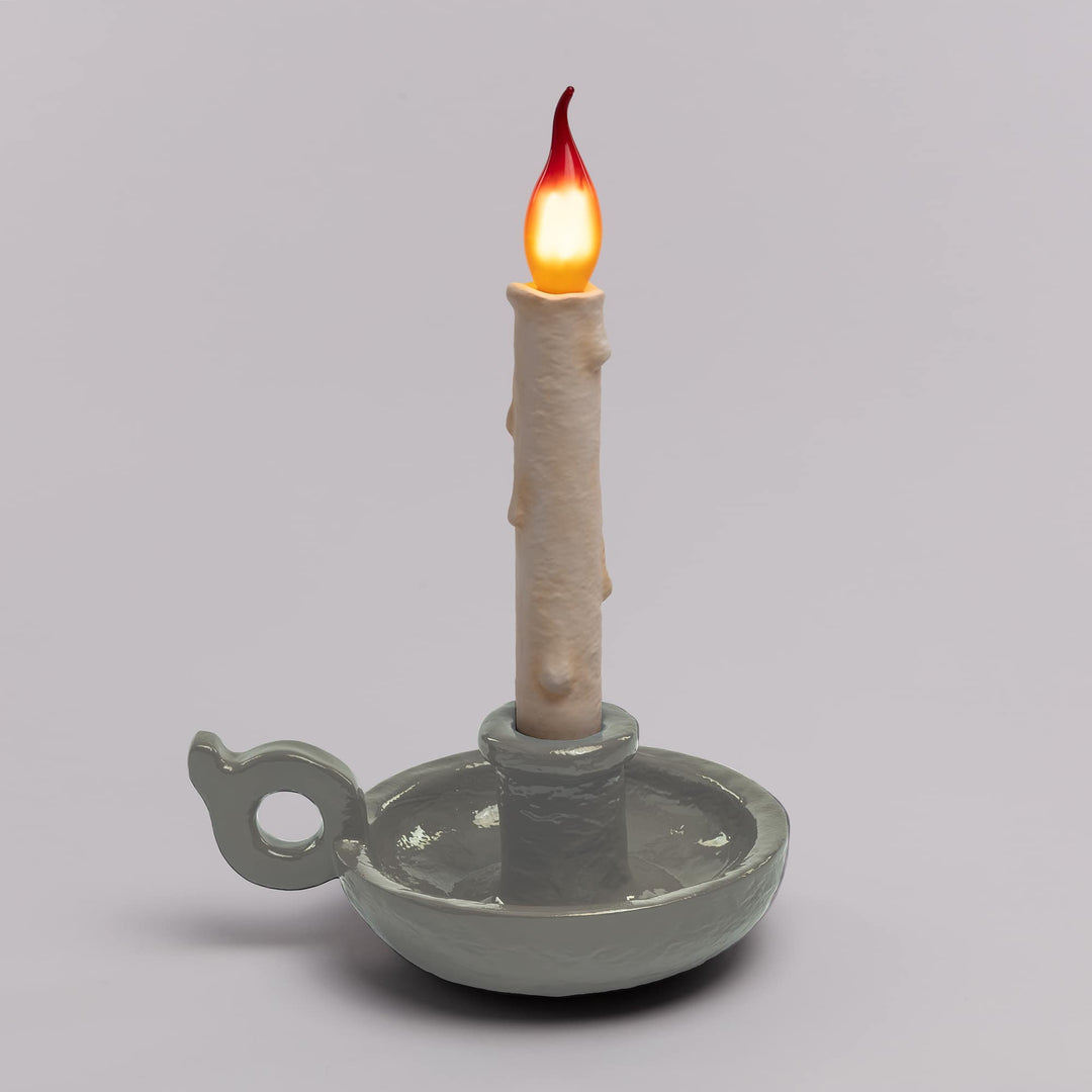 Seletti Bugia LED Candle Lamp White, pale gray-white base on a gray backdrop, flame bulb glowing